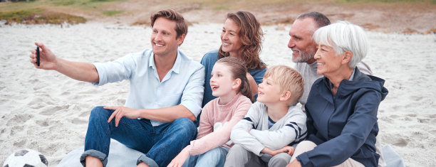 家庭，自拍和海滩上的孩子，父母和祖父母坐在沙滩上拍照。孩子们，夏天和一群亲戚在海边合影图片下载