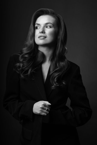 美丽的女人与深色西装和波浪的头发工作室肖像图片下载
