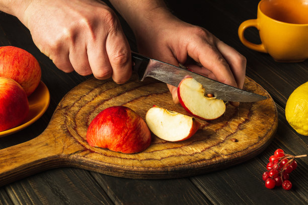 厨师在砧板上切苹果做果盘或果汁。苹果饮食中含有一套维生素。厨房餐桌上的工作环境。图片下载