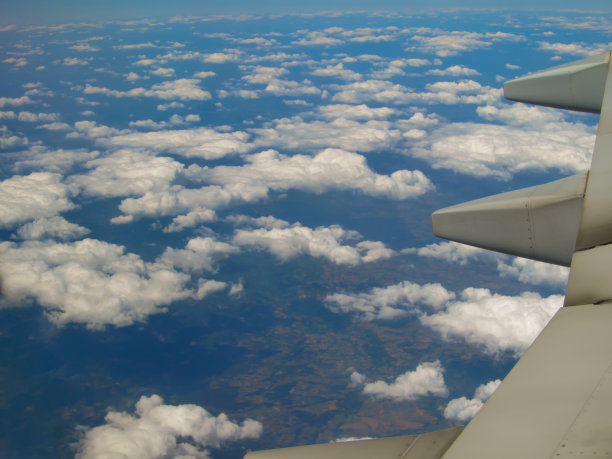 飞在地面和云层之上的飞机的机翼图片下载