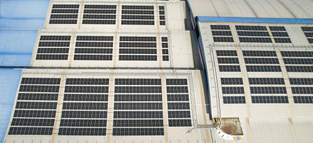太阳能电池板安装在工厂屋顶，绿色和可重复使用的能源概念图片下载