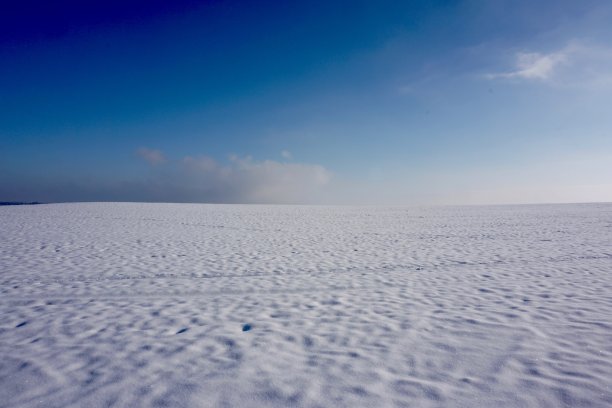 天空与白雪覆盖的大地的分离。湛蓝的天空和白雪覆盖的大地。两个人走在蓝天下的雪地里。远处，有两个人在雪地里走着。图片下载