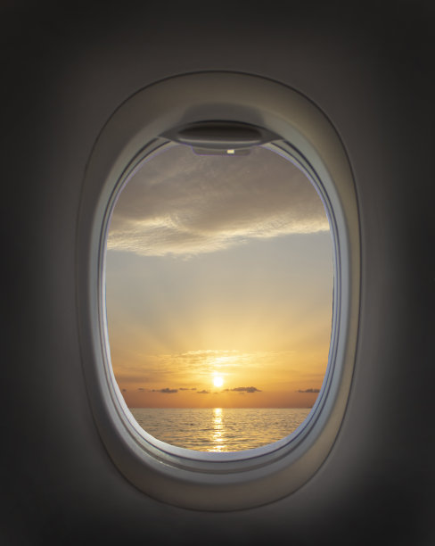 飞机窗口有美丽的天空。飞机的窗户。海景，日落和云彩。旅游理念。新景点图片下载