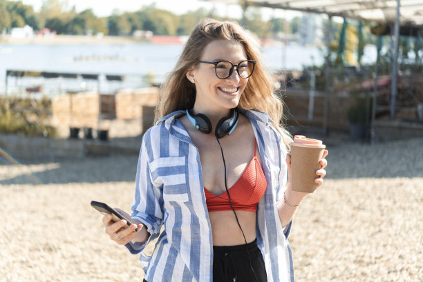 一个美丽的年轻女子在海滩上享受和在线工作的肖像图片下载