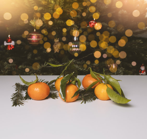 圣诞节背景，普通话。橘子后面的桌子上有一棵圣诞树。照片。图片下载