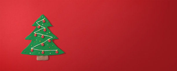 姜饼圣诞树形状的饼干，用橡皮泥手工制作，红色渐变背景与复制空间。圣诞和新年贺卡概念图片下载