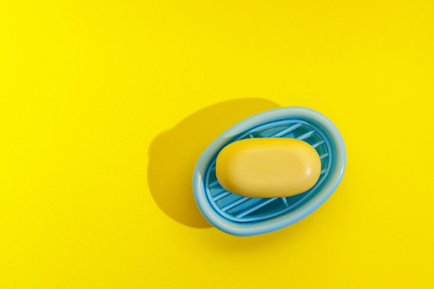 黄色背景的浅蓝色肥皂盒中有黄色肥皂图片下载