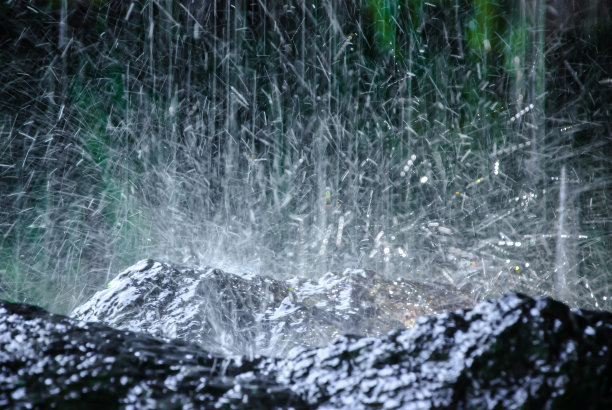 水从岩石上滴落下来，溅起光滑湿润的棕色岩石。水花纹理与模糊的背景。哭泣的岩石。美丽与活力图片下载