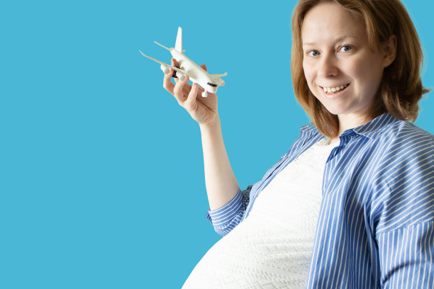 孕妇与一架飞机在她的手在蓝色背景，怀孕和航空旅行图片下载