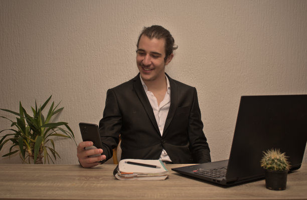 年轻的商人在工作。一只手拿着手机，另一只手拿着笔记本电脑图片下载