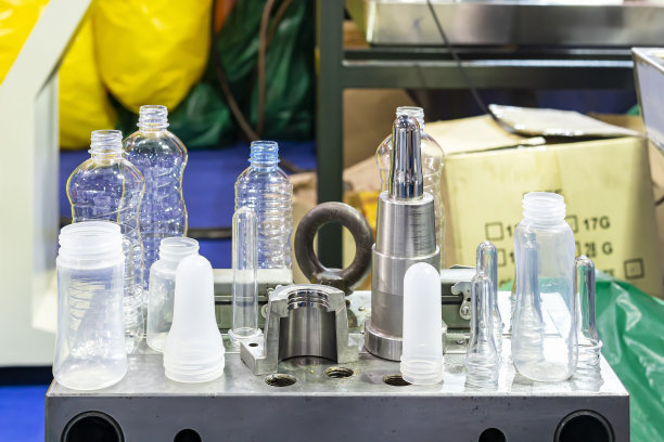 各种样品透明塑料瓶和其他颜色以预成型原料放置在工业吹瓶工艺的金属模具上图片下载