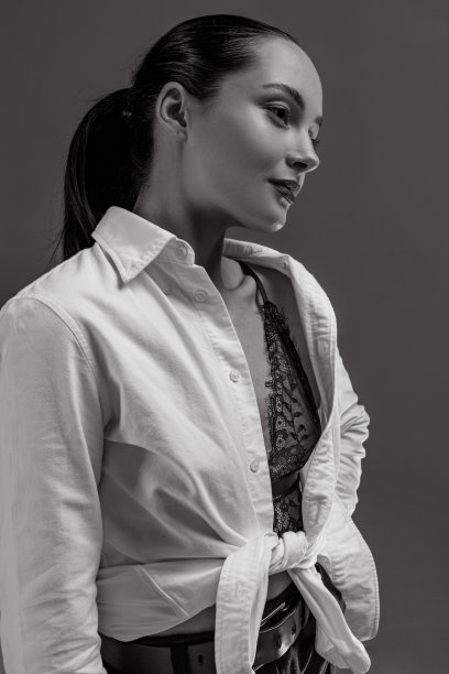 年轻女子的肖像在解开衬衫对灰色背景。图片下载