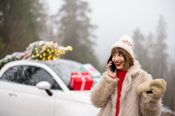 在山间，一名女子带着手机驾车旅行，车上装饰着圣诞装饰图片下载