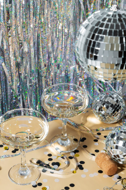 新年快乐庆祝概念主题与近距离对两杯香槟与闪亮的银色迪斯科球和五彩纸屑。新潮的派对时间符号概念图片下载