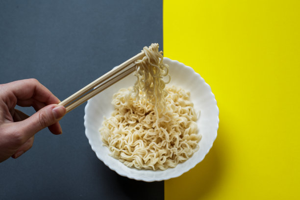 白色盘子里的方便面。用筷子手握面条。图片下载
