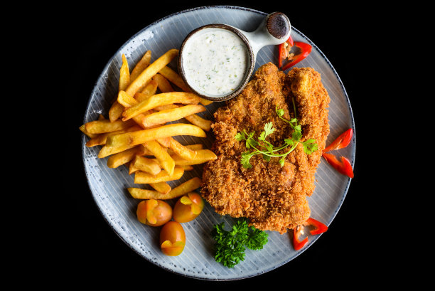 猪排牛排与蔬菜在蓝色盘子隔离在黑色背景俯视图图片下载