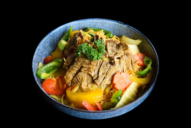 炖牛肉，面条和蔬菜在一个蓝色碗孤立的黑色背景侧视图图片下载