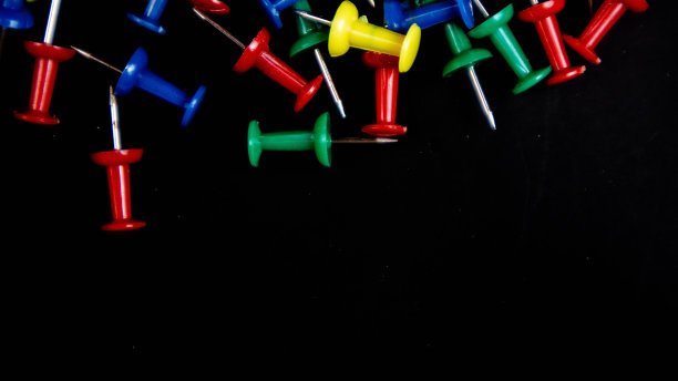 黑色背景上的彩色图钉图片下载