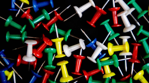 黑色背景上的彩色图钉图片下载