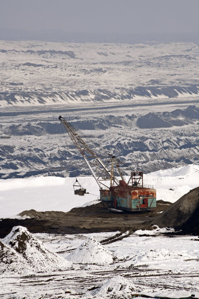 冬季条件下露天煤矿上的大型挖掘机。雪下采矿的有趣外观。图片下载