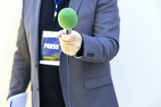 记者在新闻活动、新闻发布会或媒体采访时手持绿色麦克风。广播新闻概念与复制空间。图片下载
