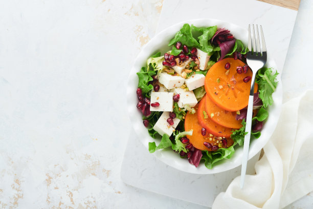 沙拉。新鲜蔬菜沙拉配羊乳酪，柿子，石榴和开心果，白盘子。健康美味的冬季圣诞沙拉。健康均衡的饮食。前视图。图片下载