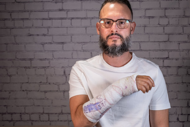 戴眼镜的男子，用夹板展示他的断臂，还有儿童画和白色t恤。图片下载