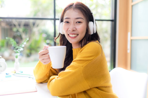 年轻女子在完成工作后，高兴地听音乐放松身心。生活方式女孩使用笔记本电脑在家里的客厅开会和工作。生活方式的概念图片下载