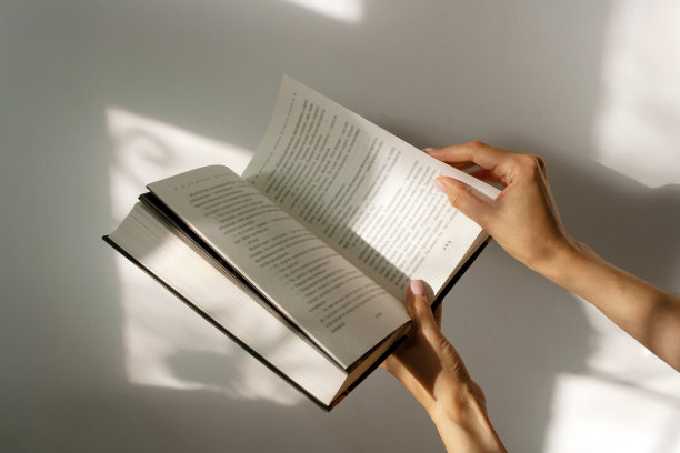 女孩翻着书，窗外的影子落在书页上图片下载