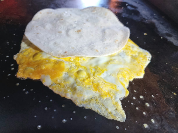 薄饼卷(Roti)。烤肉串和鸡蛋一起在黑铁锅上煎着。图片下载