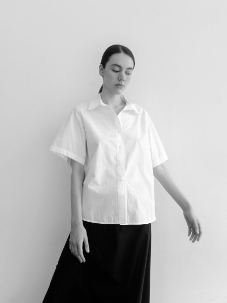 美丽的年轻女子穿着时尚简约的衣服斯堪的纳维亚风格白色短袖衬衫长宽黑色长裙时装模特摆造型看起来富有表现力自信漂亮时装模特工作室肖像在光背景图片下载