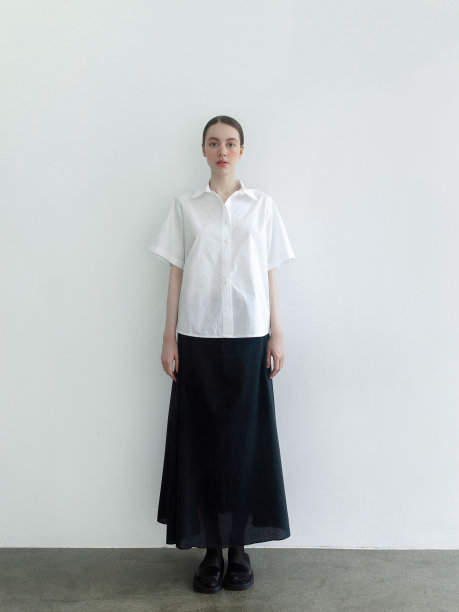 美丽的年轻女子穿着时尚简约的衣服斯堪的纳维亚风格白色短袖衬衫长宽黑色长裙时装模特摆造型看起来富有表现力自信漂亮时装模特工作室肖像在光背景图片下载