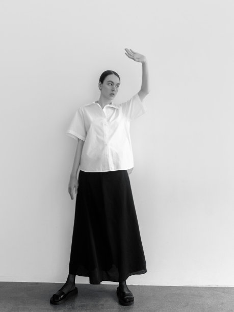 美丽的年轻女子穿着时尚简约的衣服斯堪的纳维亚风格白色短袖衬衫长宽黑色长裙时装模特摆造型看起来富有表现力自信漂亮时装模特工作室肖像在光背景图片下载