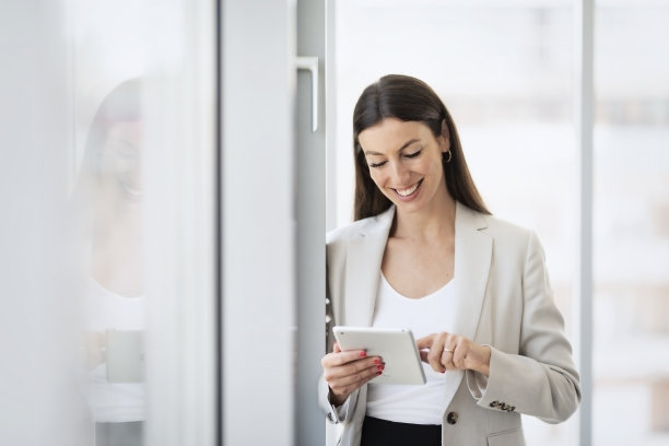 迷人的女商人站在一个现代化的办公室，同时使用一个数字平板电脑图片下载