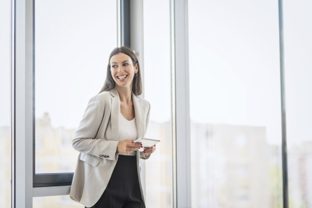 迷人的女商人站在一个现代化的办公室，同时使用一个数字平板电脑图片下载