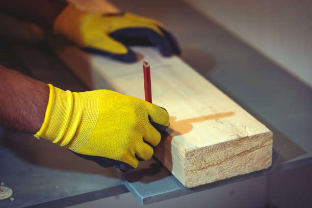 特写木匠的手正在处理木头。木匠在木板上做记号。手里拿着铅笔图片下载