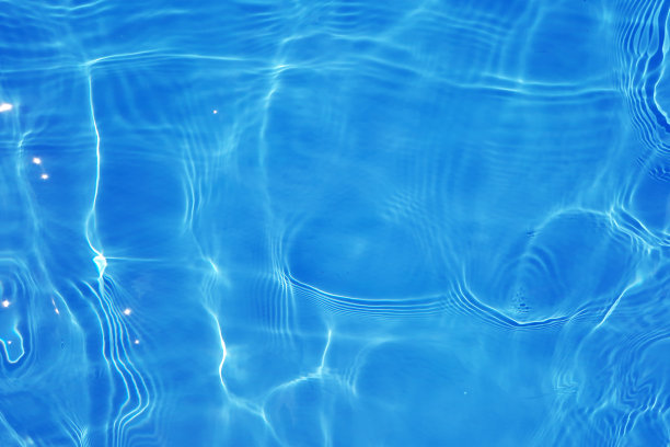 离焦模糊透明蓝色颜色清晰平静的水面纹理与飞溅和气泡。潮流抽象的自然背景。水波在阳光下带有焦散。碧水浪花闪闪发光图片下载