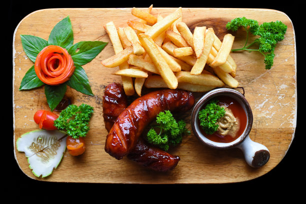 炸香肠，炸薯条和辣酱在木板上隔离在黑色背景俯视图图片下载