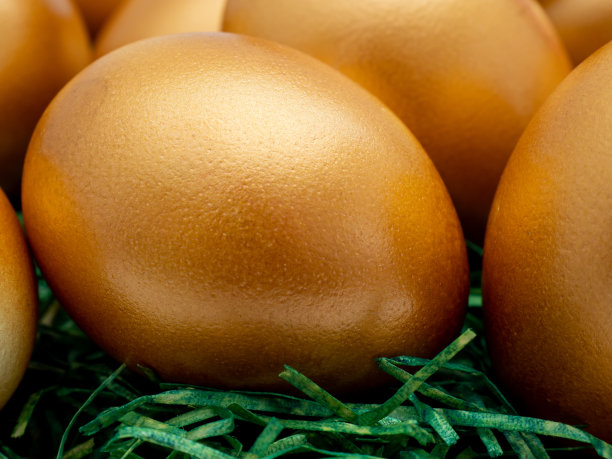 金蛋放在白底的柳条篮子里。金鸡蛋。图片下载