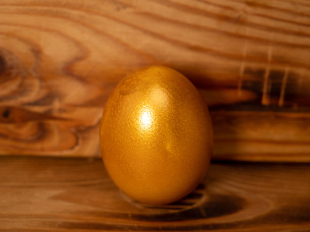 木制背景上的金蛋。金鸡蛋。图片下载