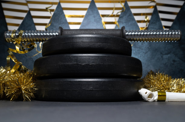 健身跨年作文。健身房哑铃杠铃重量板和金色装饰。新年锻炼计划。图片下载