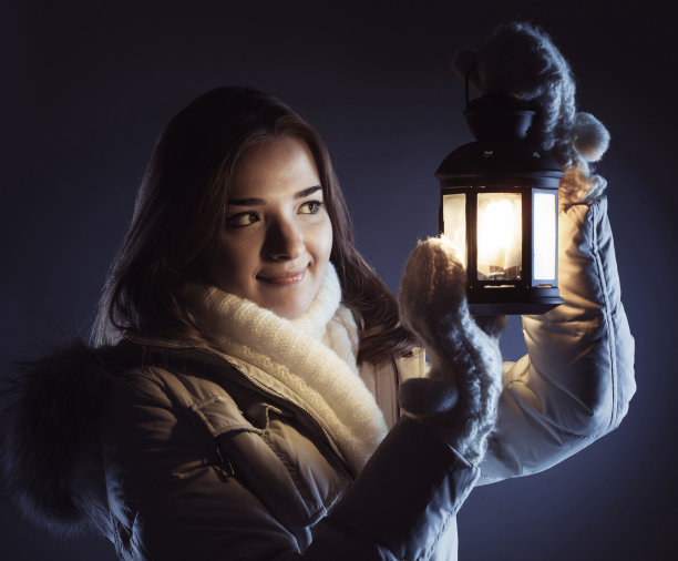 美丽的女孩在冬雪和圣诞灯笼图片下载