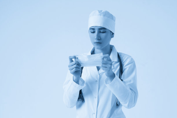 年轻女医生戴医用防护口罩的肖像，白色背景，复制空间图片下载