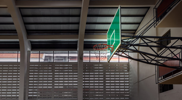 篮球玻璃纤维篮板与橙色篮球框金属环和白色橙色篮球馆网的侧面视图。图片下载