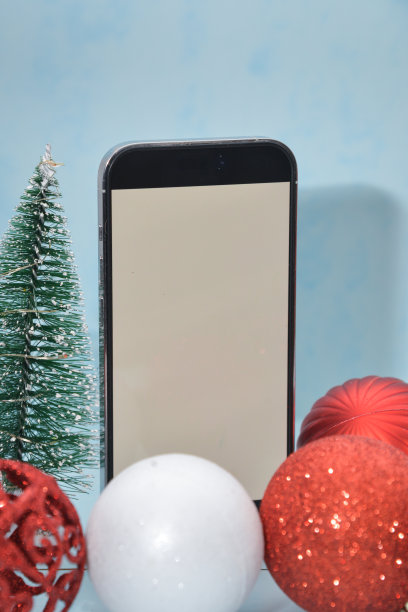 里加/拉脱维亚——2022年12月4日:全新的现代手机白屏。蓝色背景上闪闪发光的圣诞装饰品。圣诞礼物概念。图片下载