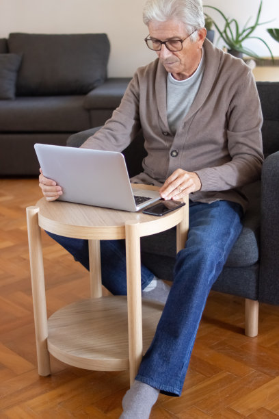 现代老人在家里使用笔记本电脑图片下载