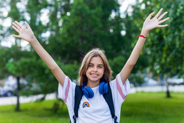 十几岁的女孩带着背包和耳机在公园回到学校的概念图片下载
