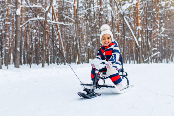 小女孩在下雪的冬天在公园玩雪橇下山图片下载