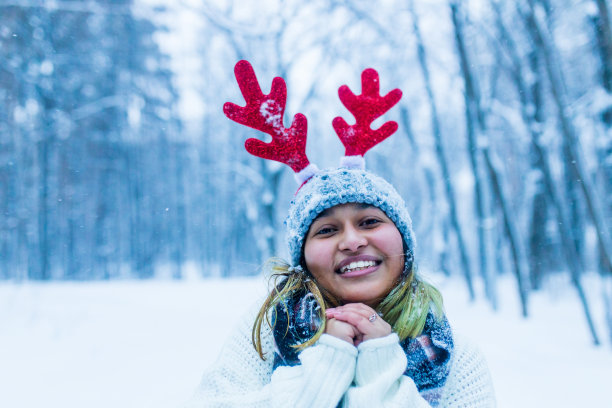 快乐的印度女人玩得开心，享受初雪戴有趣的帽子鹿角图片下载