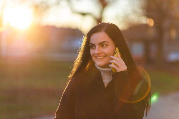美丽的年轻女子在户外散步时打电话图片下载